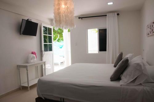 a bedroom with a large white bed with a chandelier at Le Castel Blanc Hotel Boutique in San Andrés