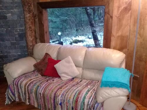 a white couch with pillows sitting in a room with a window at Domos Entre Bosques in Malalcahuello