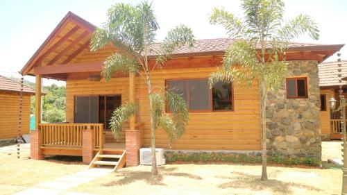a wooden cabin with a porch and two palm trees at Carmen Hotel & Villas in Jarabacoa