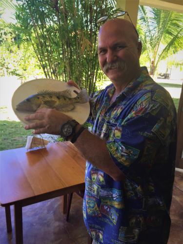 a man is holding a fish on a table at Royale Manor in Corozal