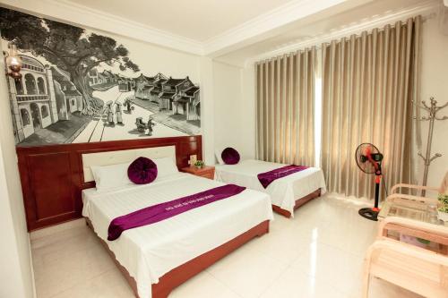 a bedroom with two beds and a painting on the wall at Dang Quang Guesthouse in Ha Long