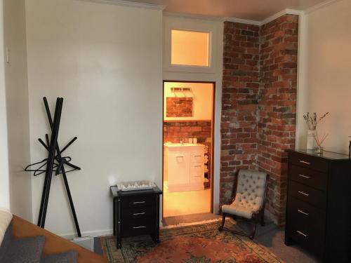 a room with a door and a chair and a brick wall at Private, comfortable studio. in Wellington