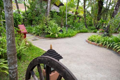 a walkway through a garden with a bench and trees at Amata Resort & Spa, Ngapali Beach in Ngapali