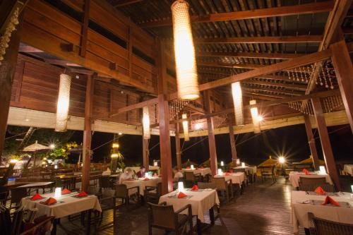 a restaurant with white tables and chairs and lights at Amata Resort & Spa, Ngapali Beach in Ngapali