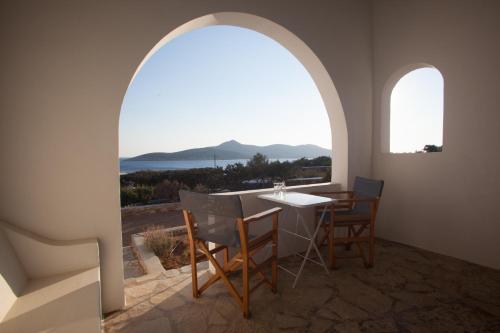a dining room with an arched window and a table and chairs at Oliaros seaside complex in Agios Georgios