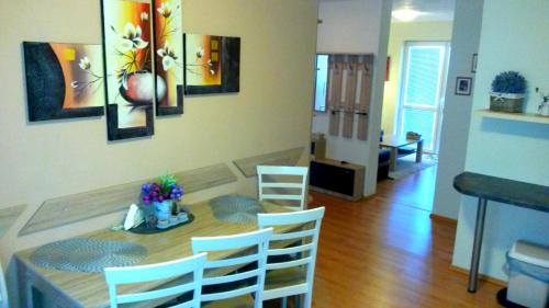 a dining room with a table with chairs and paintings on the wall at Pine Wood Apartment in Vyšné Ružbachy