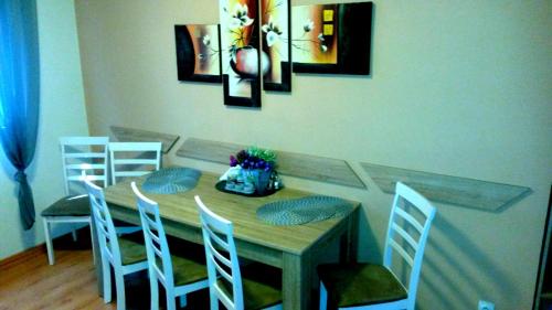 a dining room table with four chairs and a table with ahibition at Pine Wood Apartment in Vyšné Ružbachy