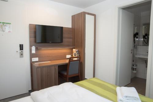 - une chambre avec un bureau et une télévision murale dans l'établissement Goethe Hotel Messe by Trip Inn, à Francfort-sur-le-Main