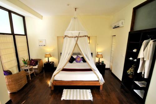 a bedroom with a bed with a canopy at Amata Resort & Spa, Ngapali Beach in Ngapali