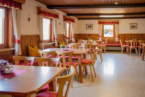 un restaurant avec des tables et des chaises en bois ainsi que des fenêtres dans l'établissement Ertlschweigerhaus Pension - Appartements - Zimmer, à Donnersbach