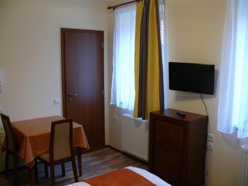 a room with a table and a television on a dresser at Tip-Top Lak Vendégház in Szilvásvárad