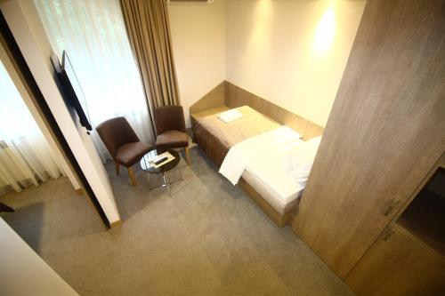 a small room with a bed and a chair at Garni Hotel Mlinarev san in Arilje