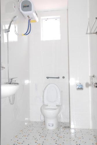 a white bathroom with a toilet and a shower at Quynh Yen Hotel in Ha Long