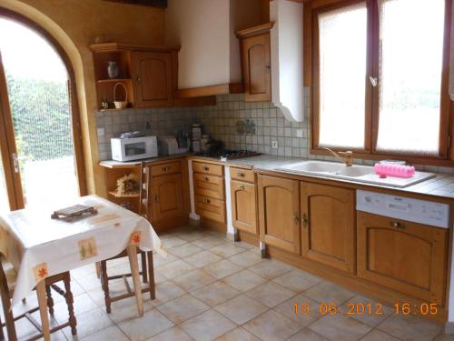 una cocina con armarios de madera y una mesa. en La Jasse De Blayac, en Roquefort-sur-Soulzon