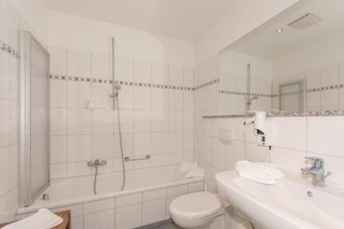 a bathroom with a toilet and a shower and a sink at Hotel Badehaus Goor in Putbus