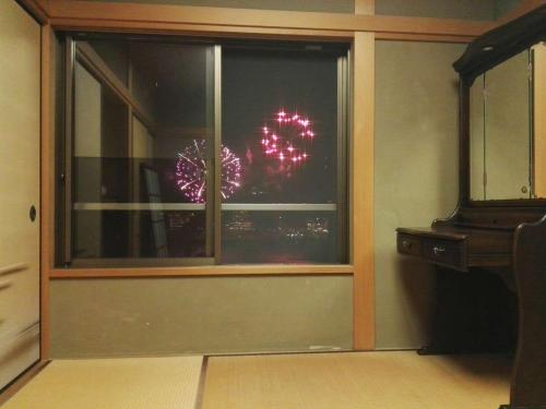 a window with a fireworks display in a room at Atami Onsen Guest House Megumi 5 minutes walk from Atami Station in Atami