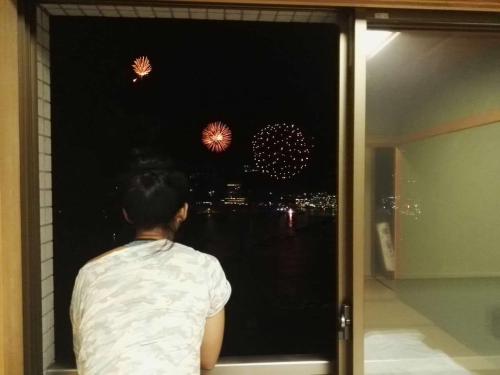 a person looking out of a window at fireworks at Atami Onsen Guest House Megumi 5 minutes walk from Atami Station in Atami
