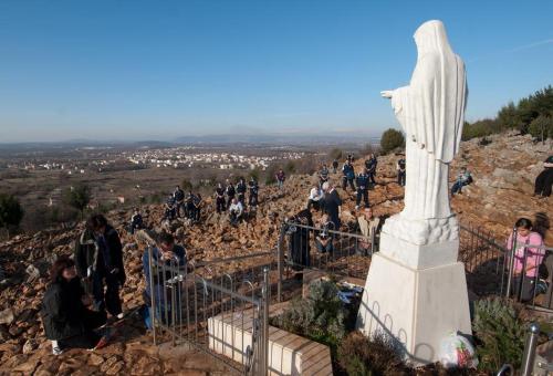 a group of people standing around a statue on a hill at Guesthouse Soče in Međugorje