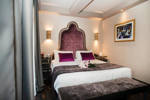 een hotelkamer met een groot bed met een paars hoofdeinde bij HT6 Hotel Roma in Rome