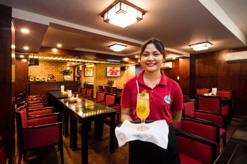 a woman holding a drink in a restaurant at Vien Dong District 7 Phu My Hung in Ho Chi Minh City