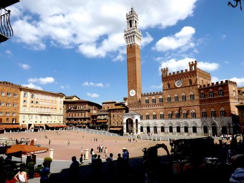 a large square with a clock tower in a city at Affittacamere Caliani in Buonconvento