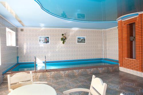 a swimming pool in a room with a table and chairs at Ideal Hotel in Vinnytsya