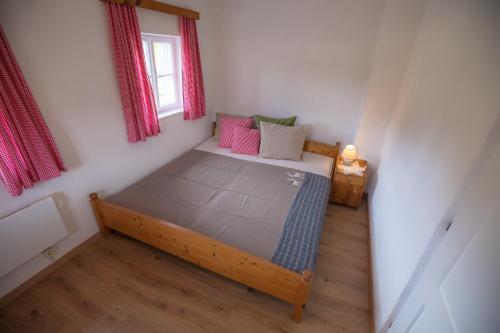 a small bedroom with a bed with pink pillows at Achentaler Bauernhäusl in Achenkirch