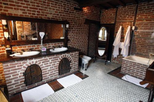 ceglana łazienka z 2 umywalkami i wanną w obiekcie Auberge Du Bon Fermier w mieście Valenciennes