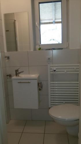 a bathroom with a toilet and a sink and a window at Room Agency Zentrum in Hannover