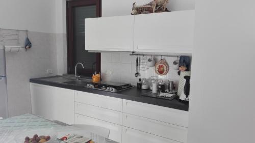cocina con armarios blancos y encimera negra en White Apartment, en Vasto