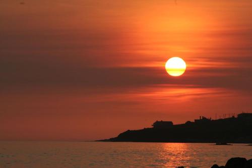 a sunset over the ocean with the sun in the sky at Ballyheigue Cliff Side and Sea View Apartment in Ballyheigue