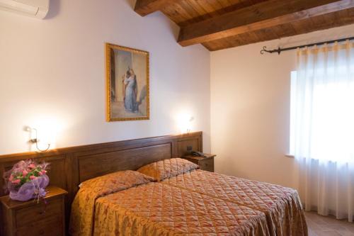a bedroom with a bed and a picture on the wall at Colleverde Country House & SPA Urbino in Urbino