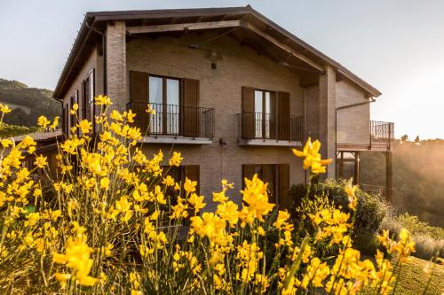 a house in the middle of a field of yellow flowers at Colleverde Country House & SPA Urbino in Urbino