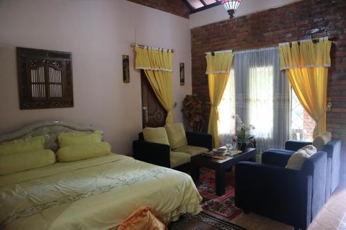 a bedroom with a bed and a couch and chairs at Princess Cottages in Sukabumi