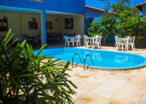 a swimming pool with chairs and a table at Pousada Pé na Areia in Pipa