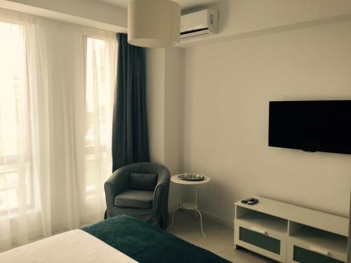 um quarto de hotel com uma cama e uma cadeira e uma televisão em Mamaia Beach Side em Mamaia