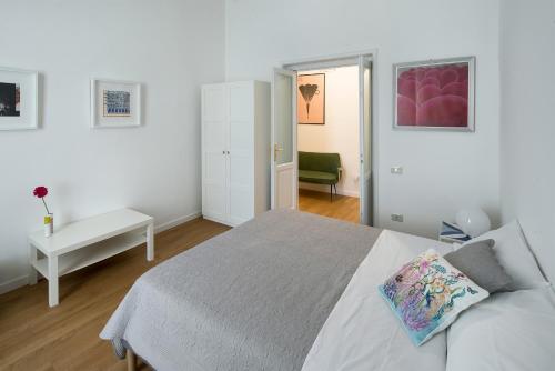 a white bedroom with a bed and a chair at A Casa di Adri in Salerno