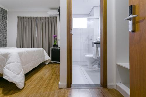 a bedroom with a bed and a bathroom with a shower at Bauru Office Hotel in Bauru