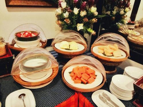 a table topped with plates and bowls of fruit at Viang Thapae Resort in Chiang Mai