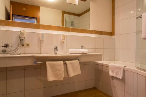 a bathroom with a sink and a mirror and towels at all inclusive Hotel Lohmann in Obergurgl
