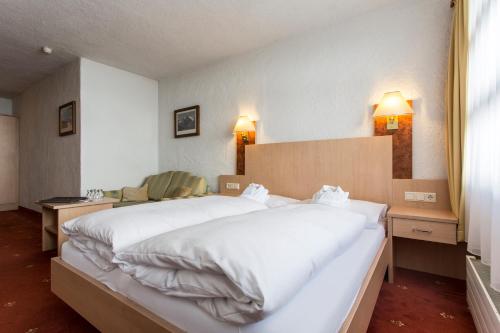 a bedroom with a large bed with white sheets at all inclusive Hotel Lohmann in Obergurgl