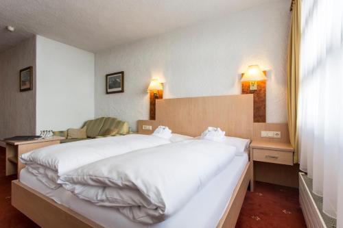 a bedroom with a large white bed and two lamps at all inclusive Hotel Lohmann in Obergurgl