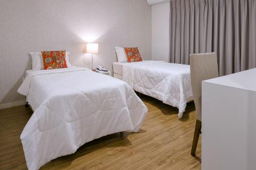 a hotel room with two beds and a table at Bauru Office Hotel in Bauru
