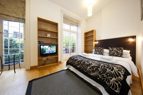 1 dormitorio con 1 cama grande y TV en Studios2Let, en Londres