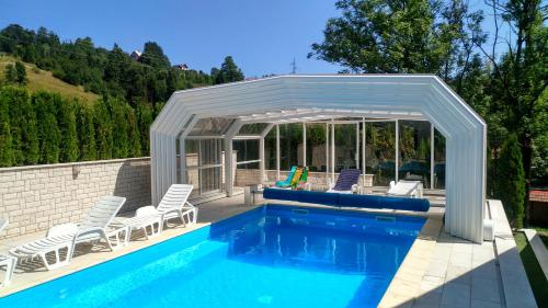 a pavilion over a swimming pool with chairs and a swimming pool at Pansion Bijela Ruža - a la carte in Ravna Gora