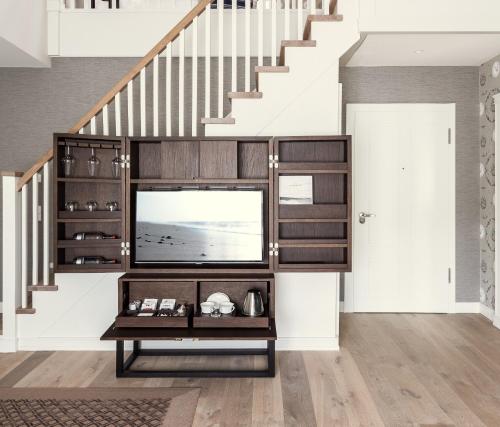 a living room with a tv and stairs at Severin's Resort & Spa in Keitum