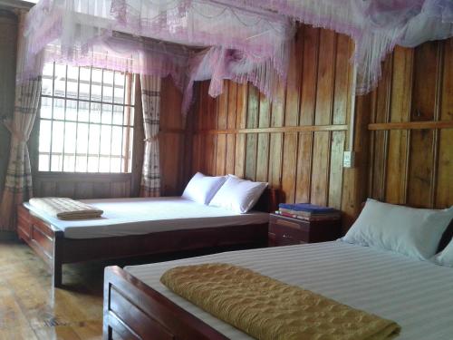 a bedroom with two beds and pink curtains at Hoàng Nguyên Homestay Ba Be in Ba Be18