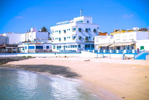 una playa con edificios blancos y agua en AVANTI Lifestyle Hotel - Only Adults, en Corralejo