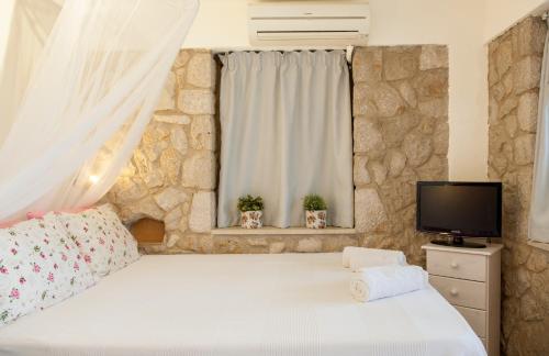 a bedroom with a white bed and a television at Villa Christianna Studios in Agios Nikitas