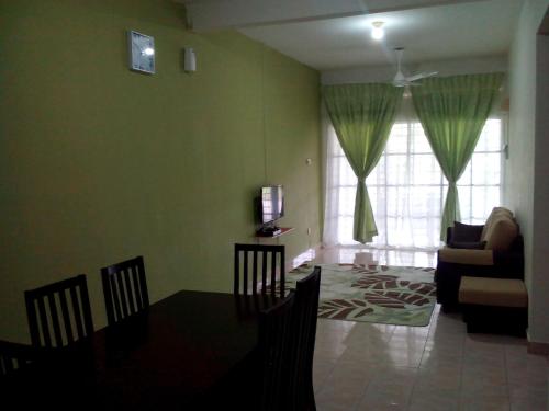 Jati Indah Homestay في ميلاكا: غرفة معيشة مع طاولة وكراسي وأريكة